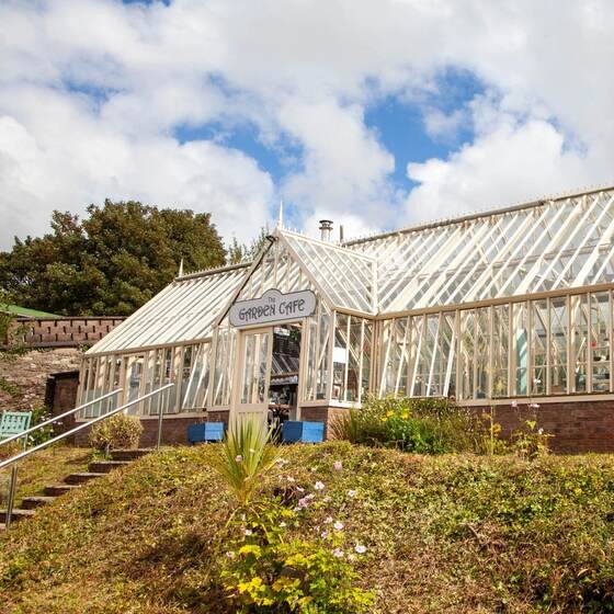 The glasshouse seen from the grass bank, with the sign over the door.